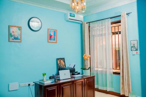 a blue room with a desk and a clock on the wall at Avek Home Stay Ngorongoro Room in Uru