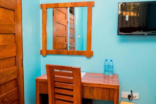 a wooden desk with a mirror and a chair at Avek Home Stay Ngorongoro Room in Uru