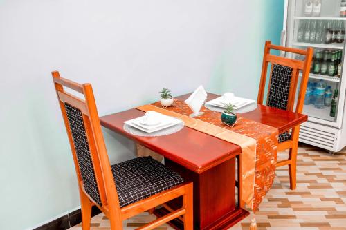 a wooden table with two chairs and a table with plates and napkins at Avek Home Stay Ngorongoro Room in Uru