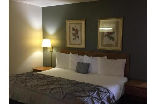 a bedroom with a large bed with white pillows at Capital O Amerihost Inn and Suites Fulton Hwy 54 MO in Fulton