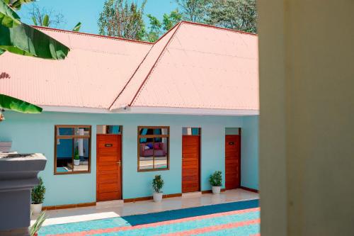 a house with orange doors and a pink roof at Avek Home Stay Ngorongoro Room in Uru