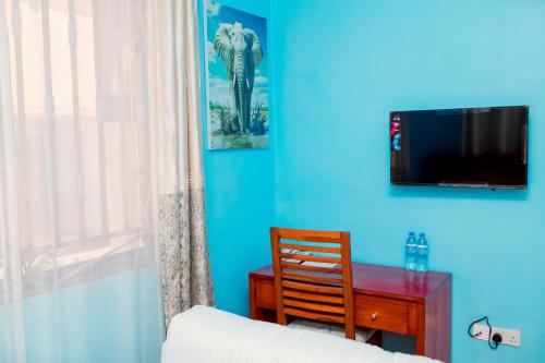 a bedroom with a desk and a tv on a blue wall at Avek Home Stay Ngorongoro Room in Uru