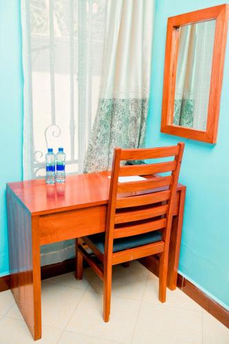 a wooden table with two bottles of water and a chair at Avek Home Stay Ngorongoro Room in Uru