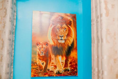 a painting of a lion and a tiger walking at Avek Home Stay Ngorongoro Room in Uru