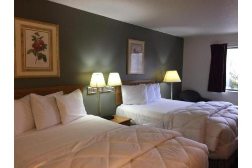 a hotel room with two beds and two lamps at Capital O Amerihost Inn and Suites Fulton Hwy 54 MO in Fulton
