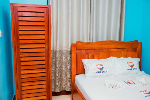 a bed with a wooden headboard and two white pillows at Avek Home Stay Ngorongoro Room in Uru