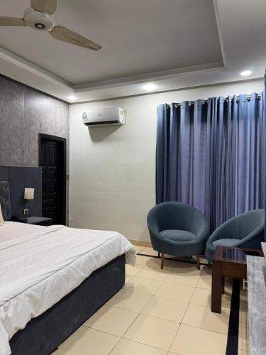 a bedroom with a bed and two chairs and a desk at Arizona Lodge 2 in Islamabad