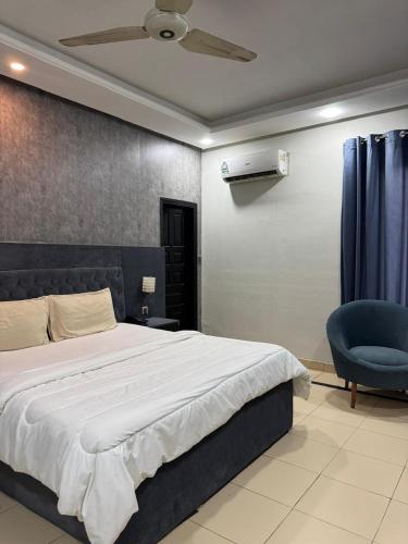 a bedroom with a bed and a blue chair at Arizona Lodge 2 in Islamabad