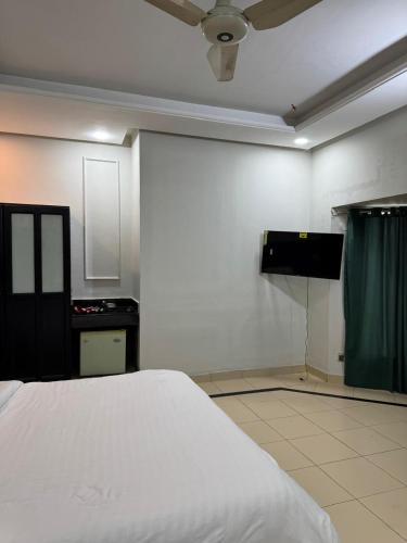 a bedroom with a white bed and a green curtain at Arizona Lodge 2 in Islamabad