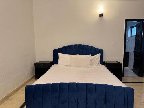 a bed with a blue headboard in a room at Arizona Lodge 2 in Islamabad