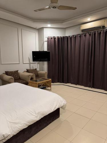 a bedroom with a bed and a tv and curtains at Arizona Lodge 2 in Islamabad