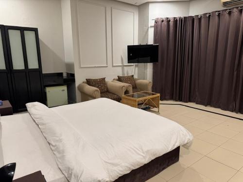 a bedroom with a bed and a couch and a tv at Arizona Lodge 2 in Islamabad
