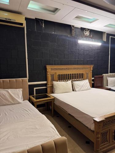 a room with two beds and a chair in it at Arizona Lodge 2 in Islamabad
