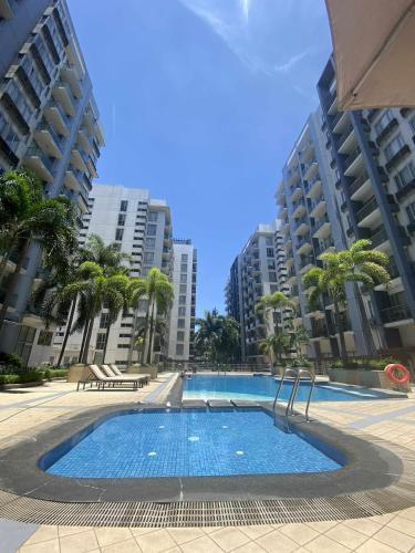ein großer Swimmingpool mit Palmen und Gebäuden in der Unterkunft Bekipay Suite at One Palm Tree right across NAIA 3 in Manila