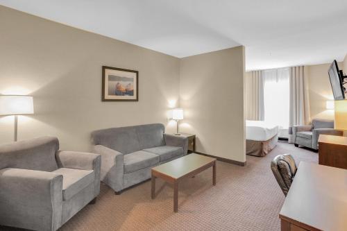 a hotel room with a couch and a bed at Duvernay Inn & Suites in Fox Creek