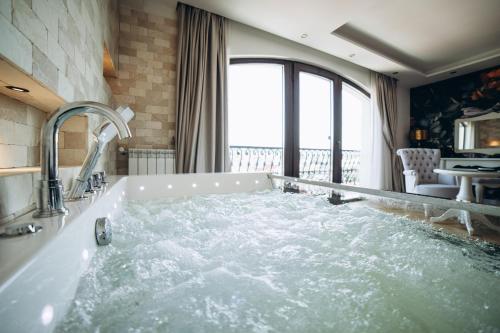 a bath tub filled with water in a bathroom at Strindberg Boutique Hotel in Topliţa