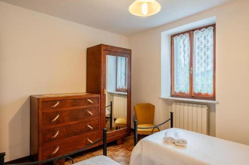 a bedroom with a bed and a dresser and a window at Casa con giardino da Toni in San Romano in Garfagnana