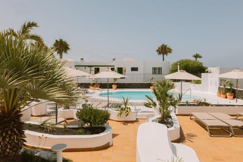 a resort with a pool and palm trees and umbrellas at Apartamentos Princesa Guayadeque in Puerto del Carmen