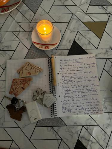a notebook and a candle on a table with a book at Alojamiento Evelyne Cal Paleta Noves de Segre in Novés de Segre
