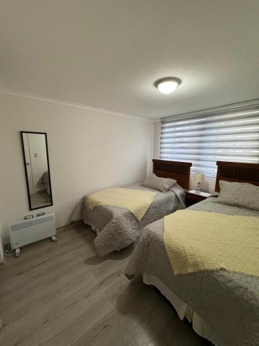 a bedroom with two beds and a mirror at Departamento Pucón 4 personas in Pucón
