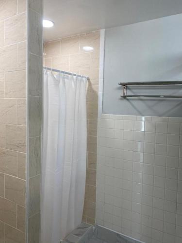 a shower with a white shower curtain in a bathroom at Mayflower Hospitality Hostel in Washington, D.C.