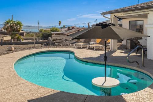 a swimming pool with an umbrella and a table with a chair at Tranquil Get Away with Lake Views in Lake Havasu City