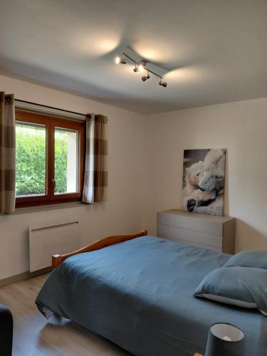 a bedroom with a blue bed and a window at Maison La Pallud in Domancy