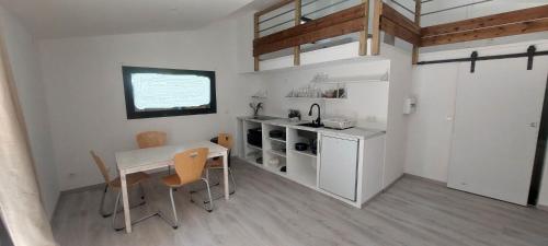 a small kitchen with a table and chairs in a room at APPARTEMENT 4 PERSONNES 100 metres du Lac jardin privé in Doussard