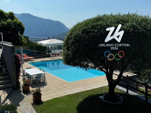 a tree in front of a swimming pool with the olympic rings at Veralto - Modern Suite with Como Lake view in Vacallo