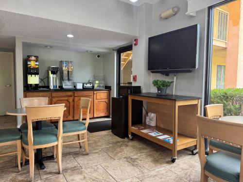 een woonkamer met een televisie en een tafel en stoelen bij Howard Johnson by Wyndham Vicksburg in Vicksburg