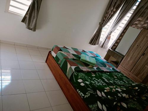 a bedroom with a bed with a green comforter and a window at Izdaan Homestay in Jasin