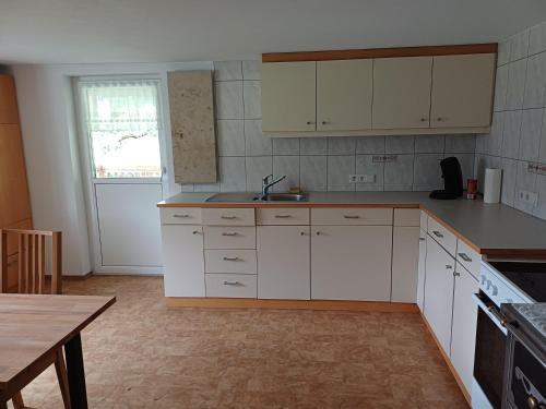 a kitchen with white cabinets and a sink and a table at Ferienwohnung Löwenblick in Thüringerberg