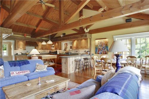 a living room with blue couches and a kitchen at Soupcon: 4 br, fireplaces, game room, sauna, hot tub, views in Stowe