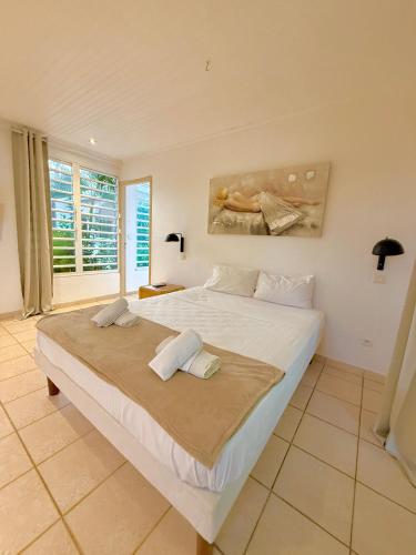 Una cama blanca grande en una habitación con ventana. en Le Domaine des 3 Caps, en Le Marin