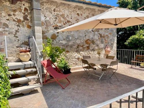 a patio with a table and an umbrella at Podere Ainzara in Montemerano
