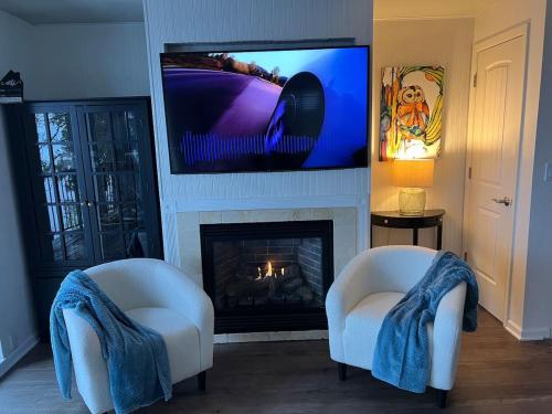 a living room with two chairs and a fireplace with a tv at Townhouse In Bayview in Bayview