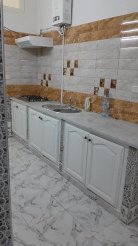 Una cocina blanca con fregadero y estufa. en DAR Mahdia, en Túnez