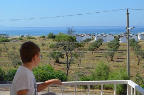 a boy standing on a balcony looking out at the ocean at Mulka Hotel in Ayvalık