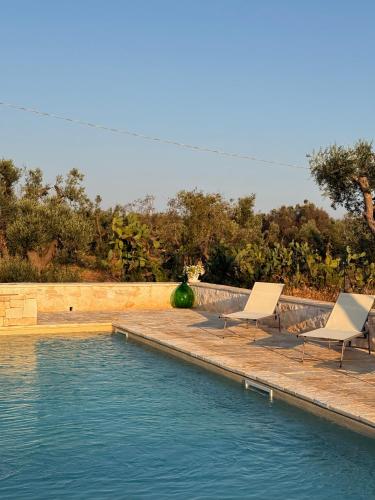 a swimming pool with two lounge chairs next to it at Trullo Tatauan in San Michele Salentino