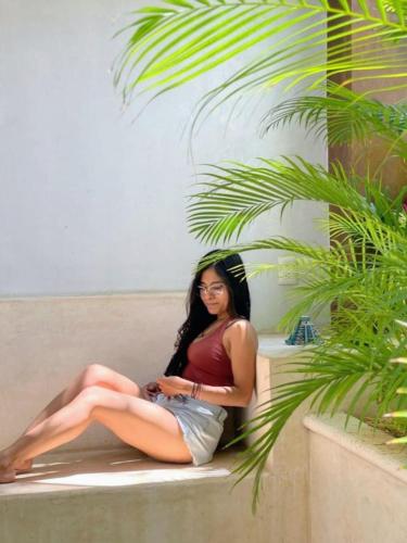 a woman sitting on a couch next to a palm tree at Casa Nicte-ha Valladolid in Valladolid