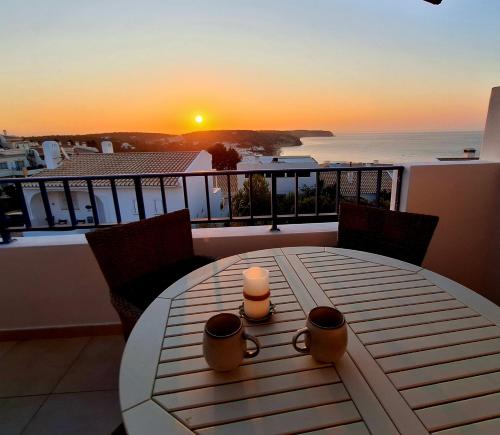 een tafel met twee kaarsen op een balkon met de zonsondergang bij Casa Calma in Salema