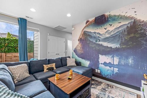 a living room with a blue couch and a large painting at 10 min to DT, Luxe 4BR w Movie Theater, Game Room in Commerce City
