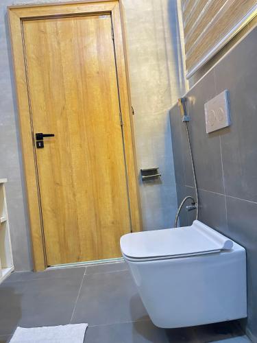 a bathroom with a toilet and a wooden door at City Styles in Abuja
