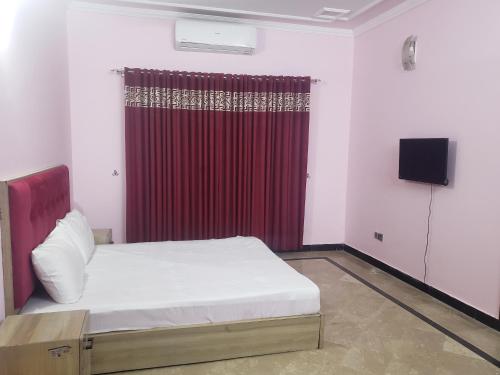 Un dormitorio con una cama y una cortina roja. en Guest Ghar Islamabad, en Islamabad