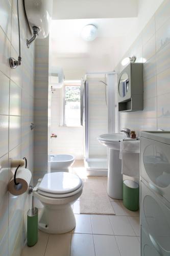 a white bathroom with a toilet and a sink at Casa fronte mare a San Saba in Messina