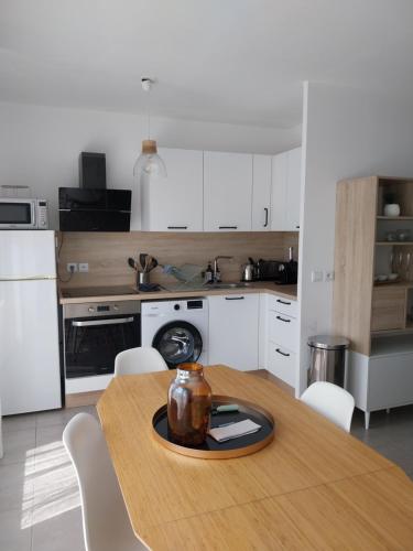 a kitchen with a wooden table and white cabinets at Appartement cosy proche Disney in Ferrières-en-Brie