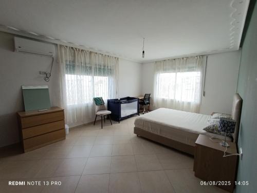 ein Schlafzimmer mit einem Bett, einem Schreibtisch und Fenstern in der Unterkunft Appartement familial au centre de Nador Ville in Nador