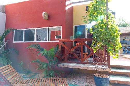 a red house with a wooden porch in front of it at Casa Nicte-ha Valladolid in Valladolid