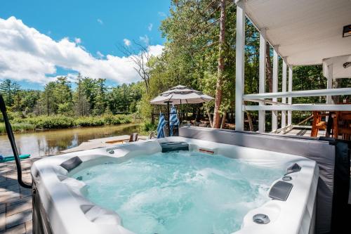 a jacuzzi tub on a deck next to a river at After Dune Delight, 5BR Home Near River in Glen Arbor