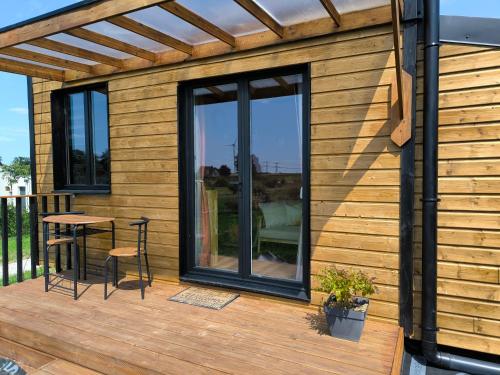 a wooden cabin with a table and chairs on a deck at La Mini Éole - Séjour insolite entre Rouen et Dieppe in Fresnay-le-Long